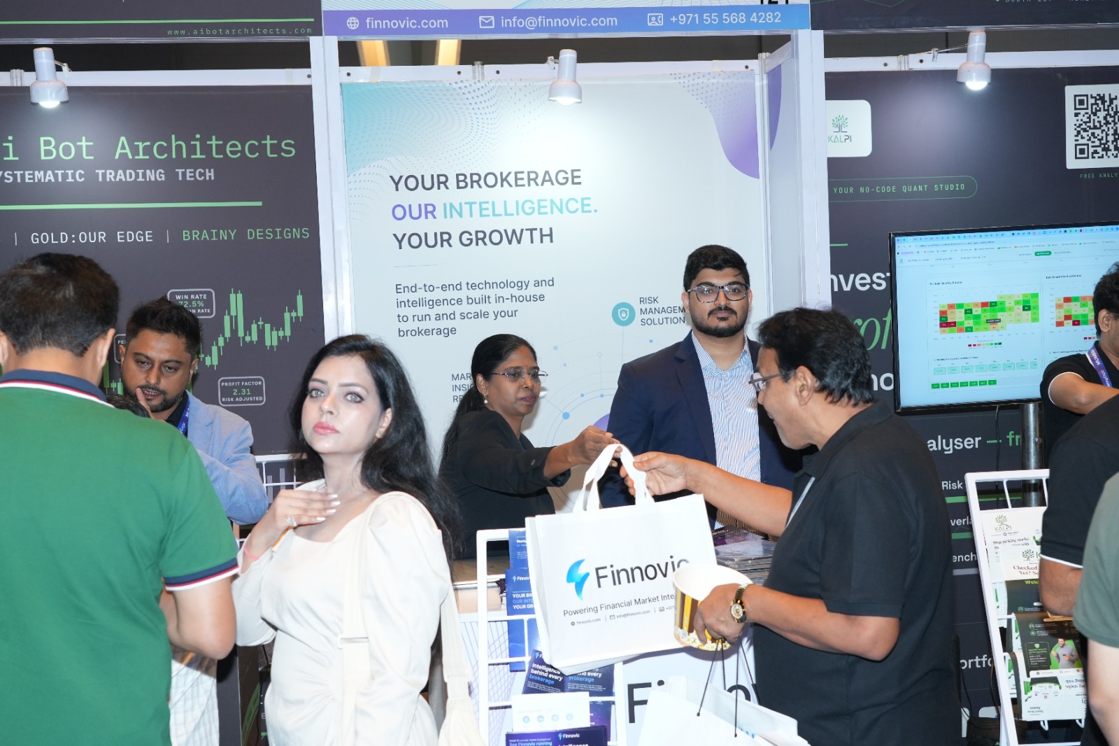 A Finnovic team member handing a branded bag to a visitor at the Money Expo India 2026 stand